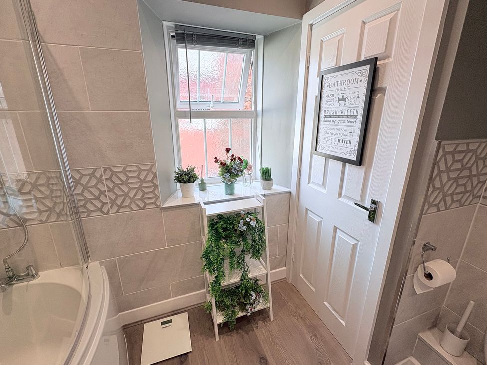 A bathroom with a bathtub, shelf, and window at The Oaks Cottage in Penrith