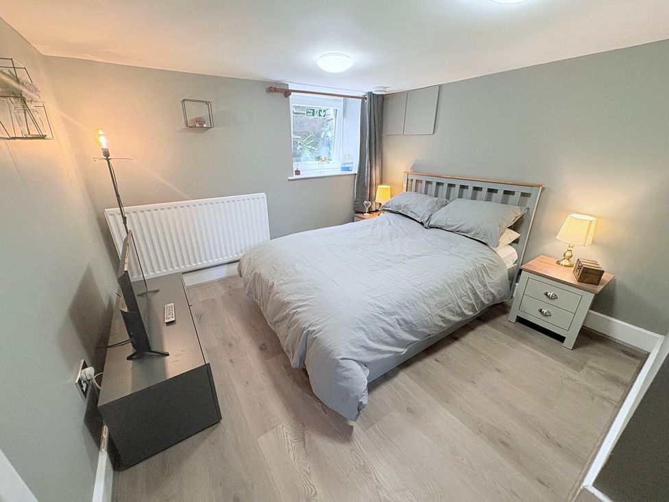 A bedroom with a bed and a television at The Oaks Cottage in Penrith