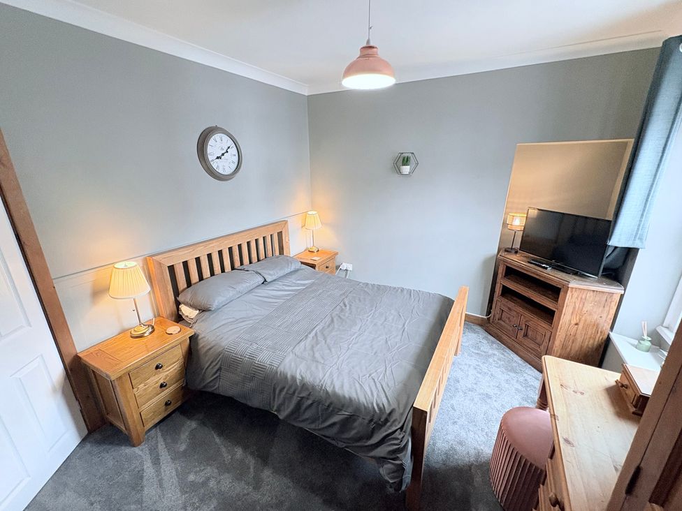 A bedroom with a bed and television at The Oaks Cottage in Penrith