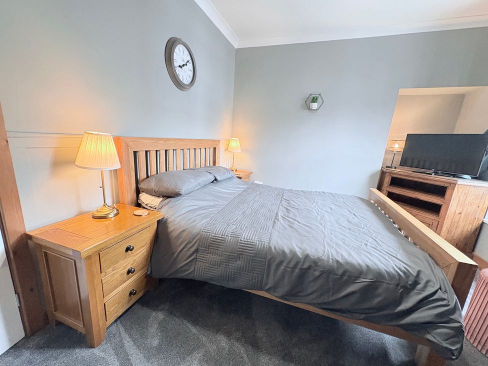 A bedroom with a bed, bedside tables, lamp and television at The Oaks Cottage in Penrith