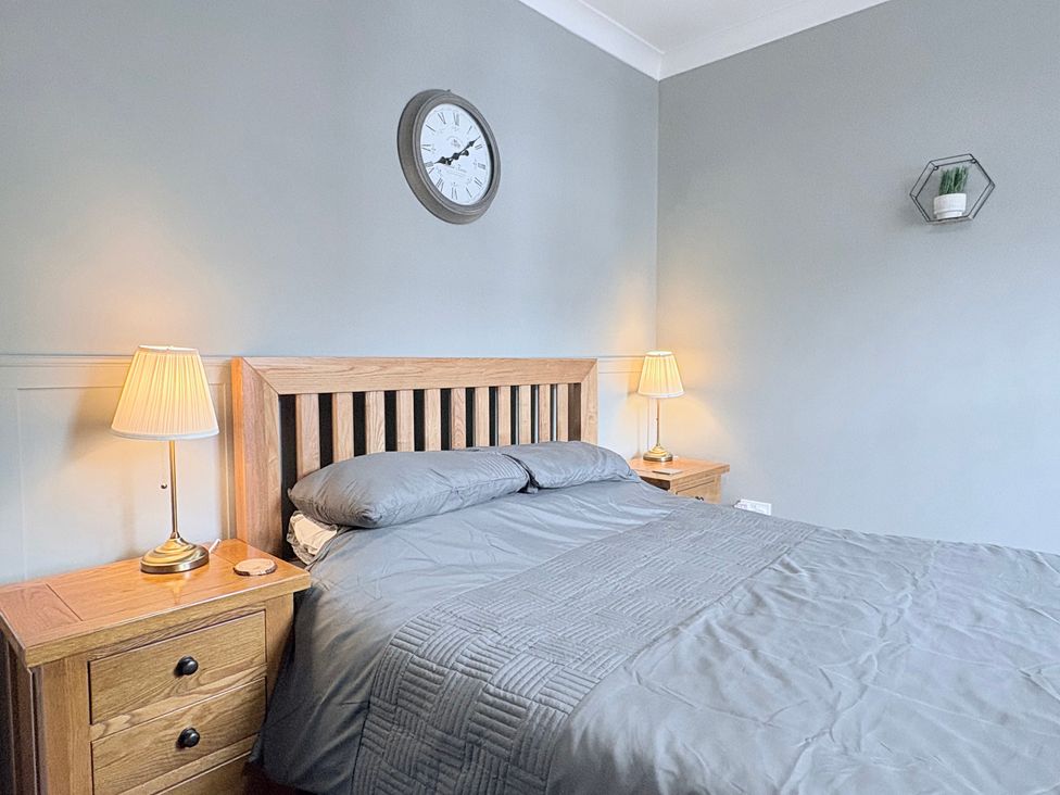 A bedroom with a bed and bedside tables at The Oaks Cottage Penrith
