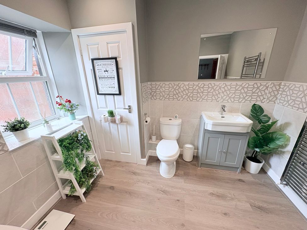 A bathroom with a sink, toilet, and window at The Oaks Cottage Penrith