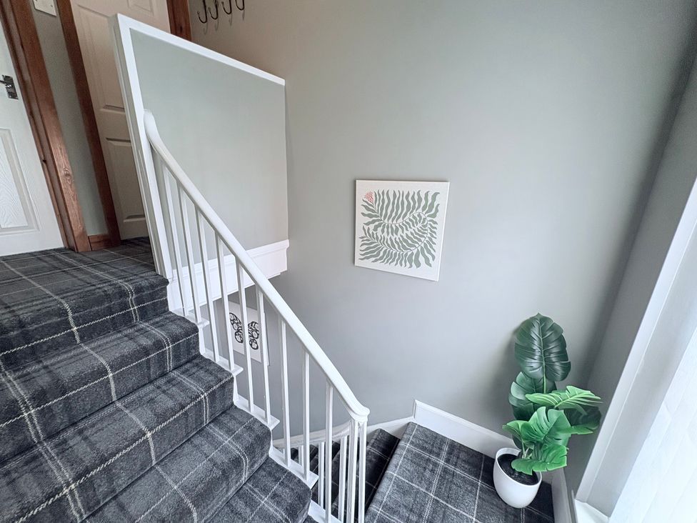 A staircase with carpet, wall art, plant, and hooks at The Oaks Cottage in Penrith