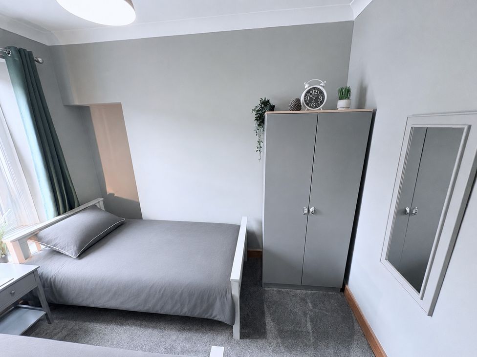 A bedroom with a bed and wardrobe at The Oaks Cottage in Penrith