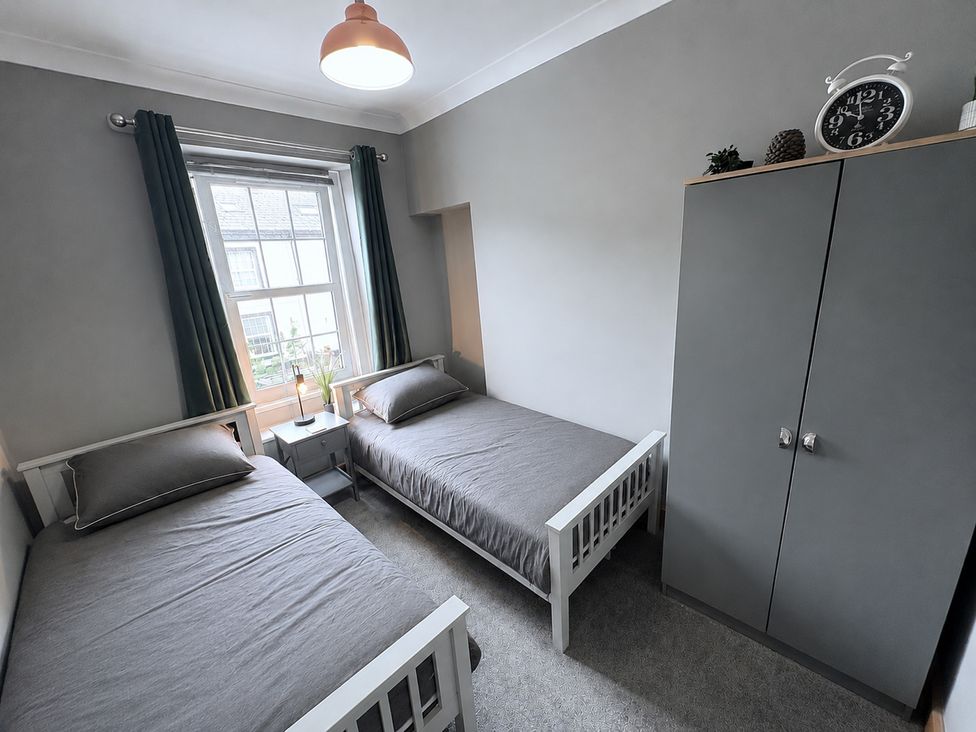 A bedroom with two beds and a wardrobe at The Oaks Cottage in Penrith