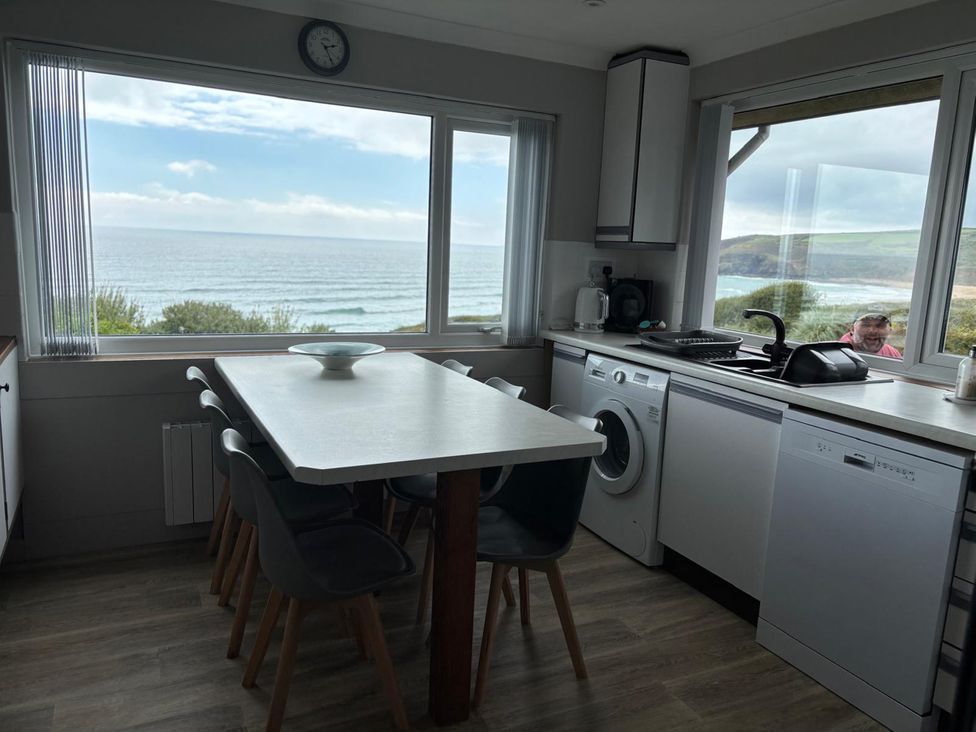 A kitchen with a table and chairs by the window overlooking the sea at Stonecroft in Praa Sands