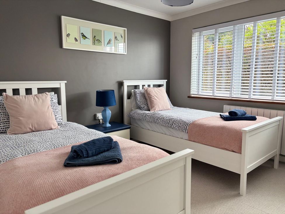 A bedroom with two single beds and a window at Stonecroft in Praa Sands