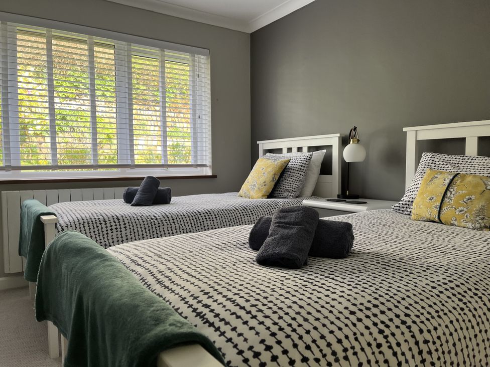 A bedroom with two beds and a window at Stonecroft in Praa Sands
