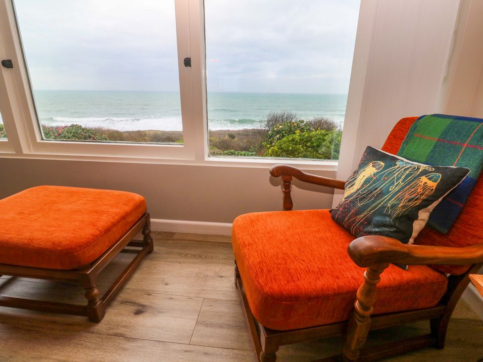 A snug area with an armchair and ottoman overlooking the ocean at Stonecroft in Praa Sands
