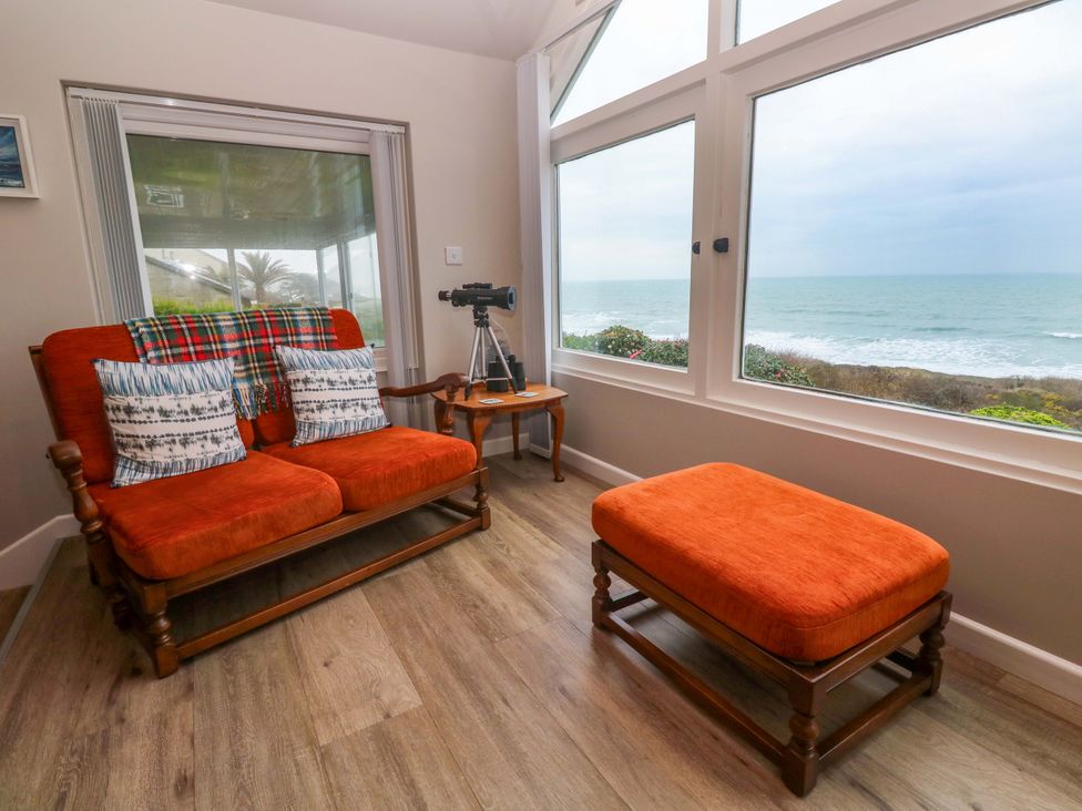 A living room with a sofa, telescope and large windows at Stonecroft in Praa Sands