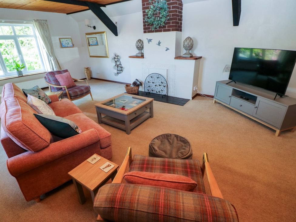 A living room with a sofa, armchair, television, and coffee table at The Stables in St Athan