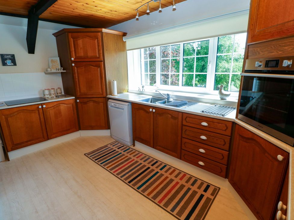 A kitchen with wooden cabinets and sink at The Stables in St Athan