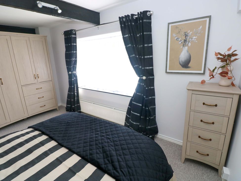 A bedroom with a bed, wardrobe, curtains, and window at The Stables in St Athan