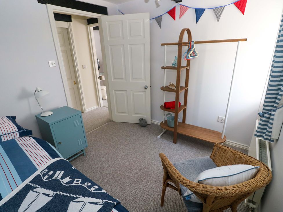 A bedroom with a bed, side table, lamp, clothes rack and chair at The Stables St Athan