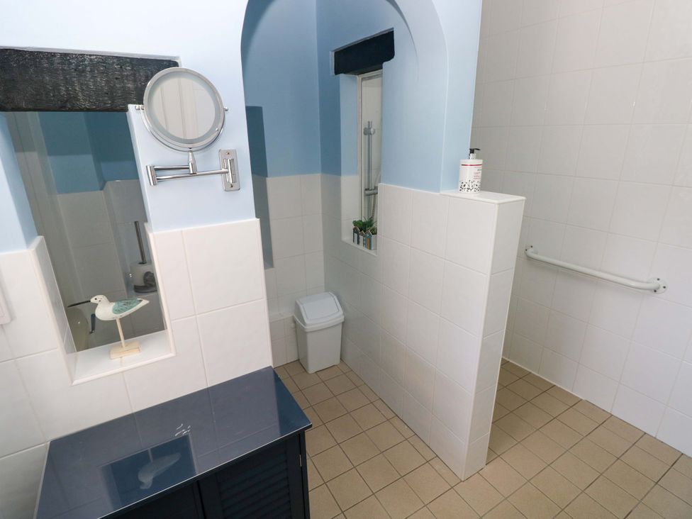 A bathroom with shower, sink, toilet, and mirror at The Stables St Athan
