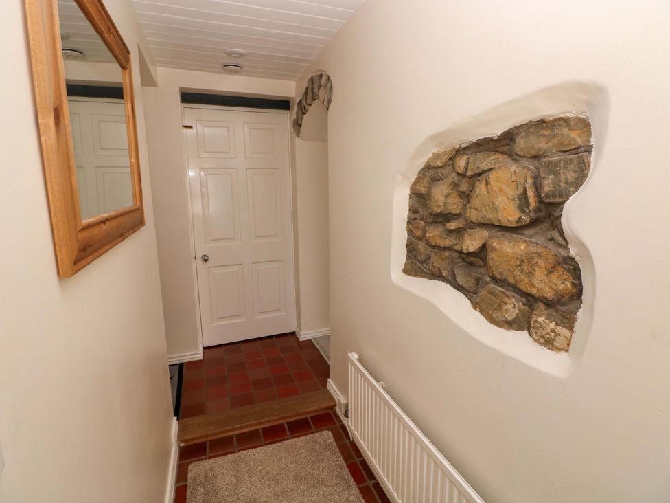 A hallway with a mirror and a stone wall at The Stables in St Athan