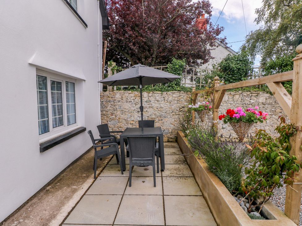 A garden with a table and chairs under an umbrella at The Stables St Athan