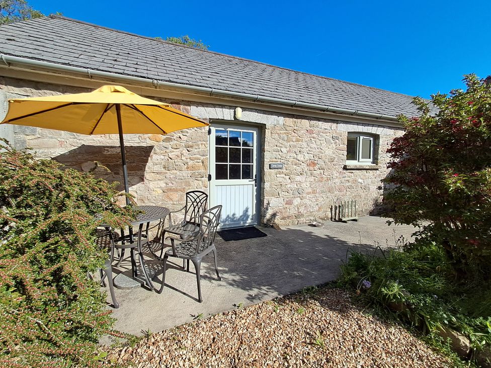 An outdoor area with a table and chairs under an umbrella at Carreg Cennen Cottage Llandeilo