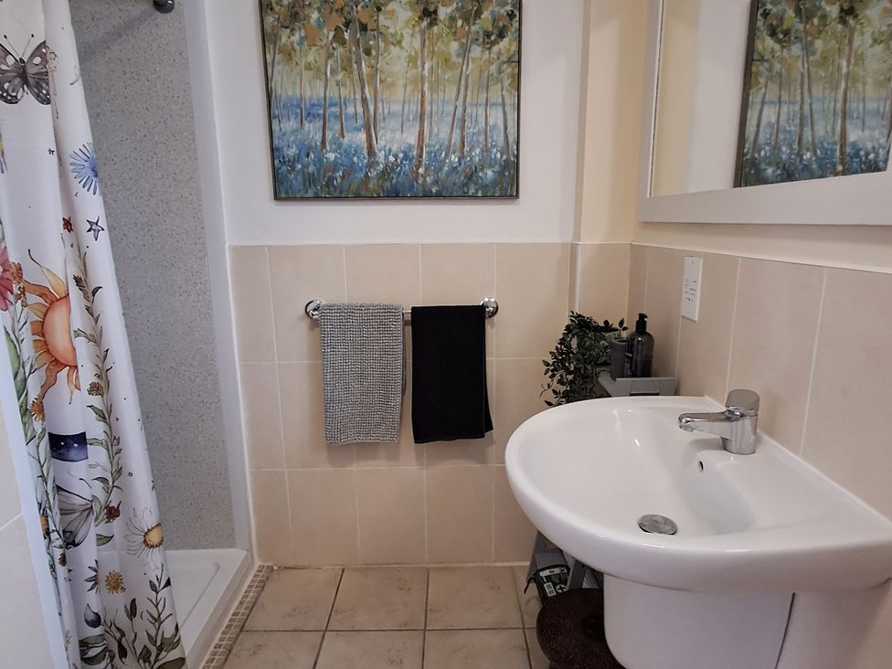 A bathroom with a shower, sink and towels at Carreg Cennen Cottage in Llandeilo