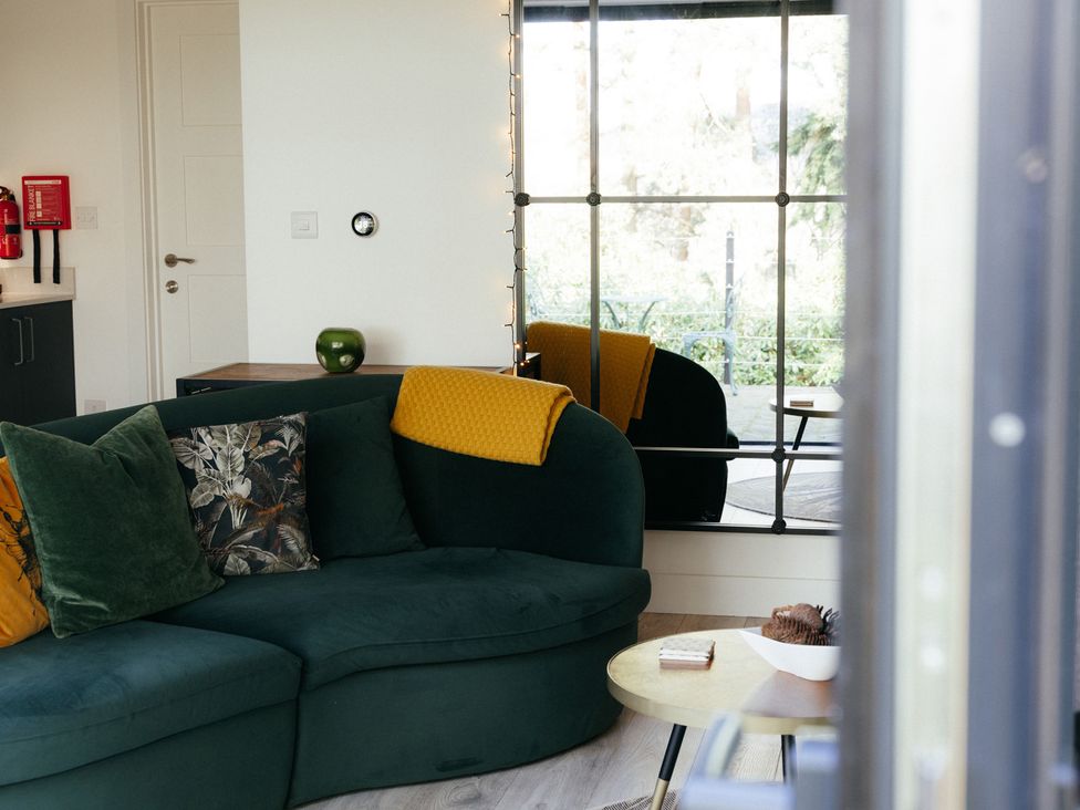 A living room with a green sofa and a side table at The Observatory Annexe in Westcott near Dorking