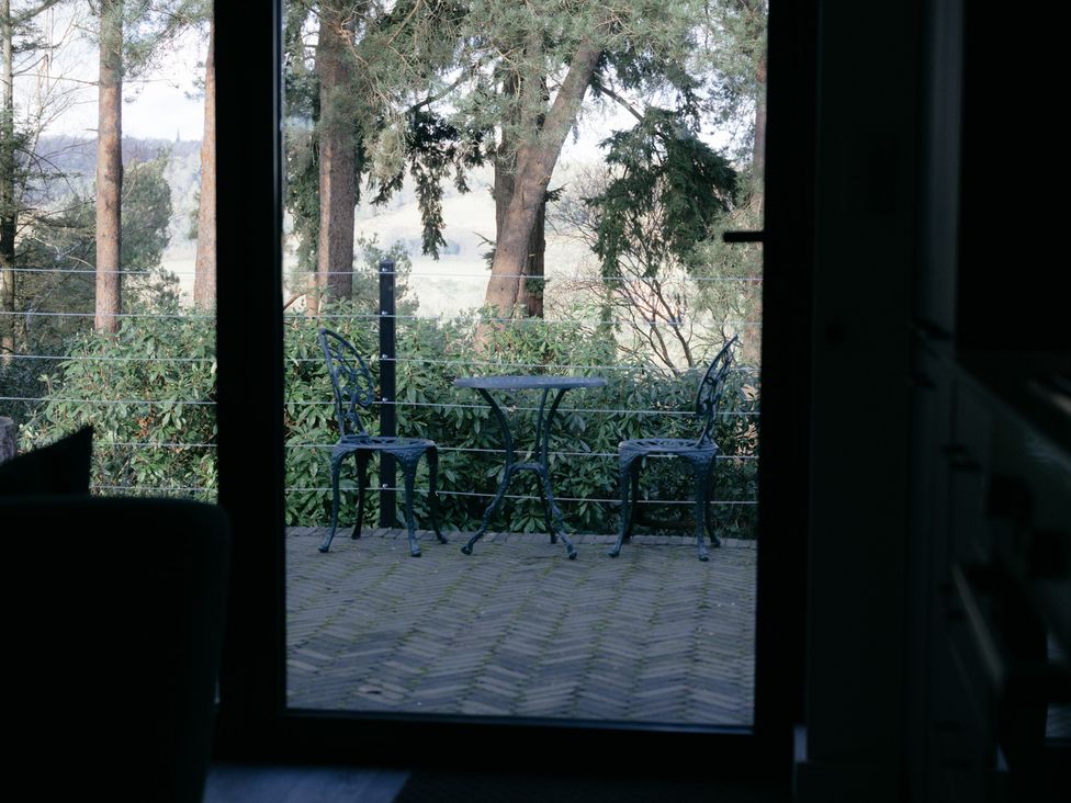 A table and chairs on a patio with views of trees at The Observatory Annexe in Westcott near Dorking