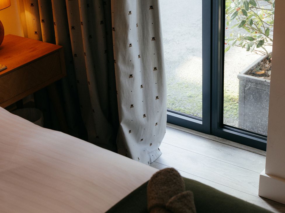 A bedroom with a side table and a window at The Observatory Annexe Westcott near Dorking