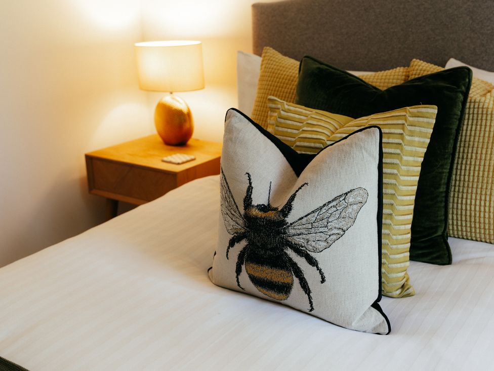 A bed with decorative pillows and a lamp on a nightstand at The Observatory Annexe Westcott near Dorking