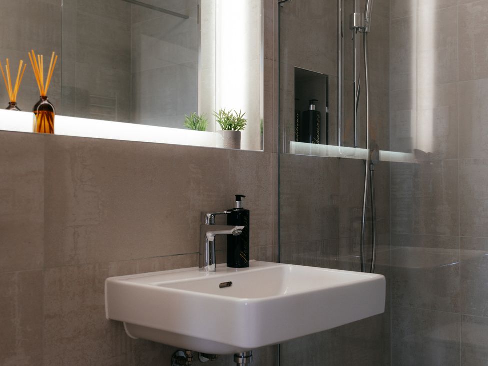 A sink with a soap dispenser and mirror in a bathroom at The Observatory Annexe in Westcott near Dorking