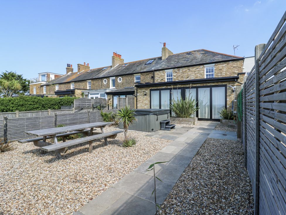 A garden with a dining table and hot tub at Coast Guard House in Swalecliffe