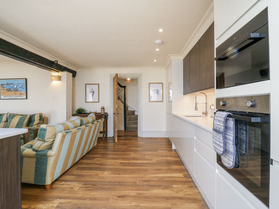 A kitchen with a sofa and staircase at Coast Guard House in Swalecliffe