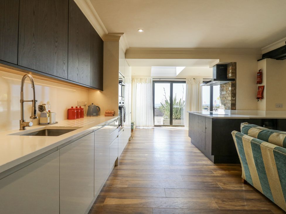 A kitchen with cabinets, sink, and sliding door at Coast Guard House in Swalecliffe
