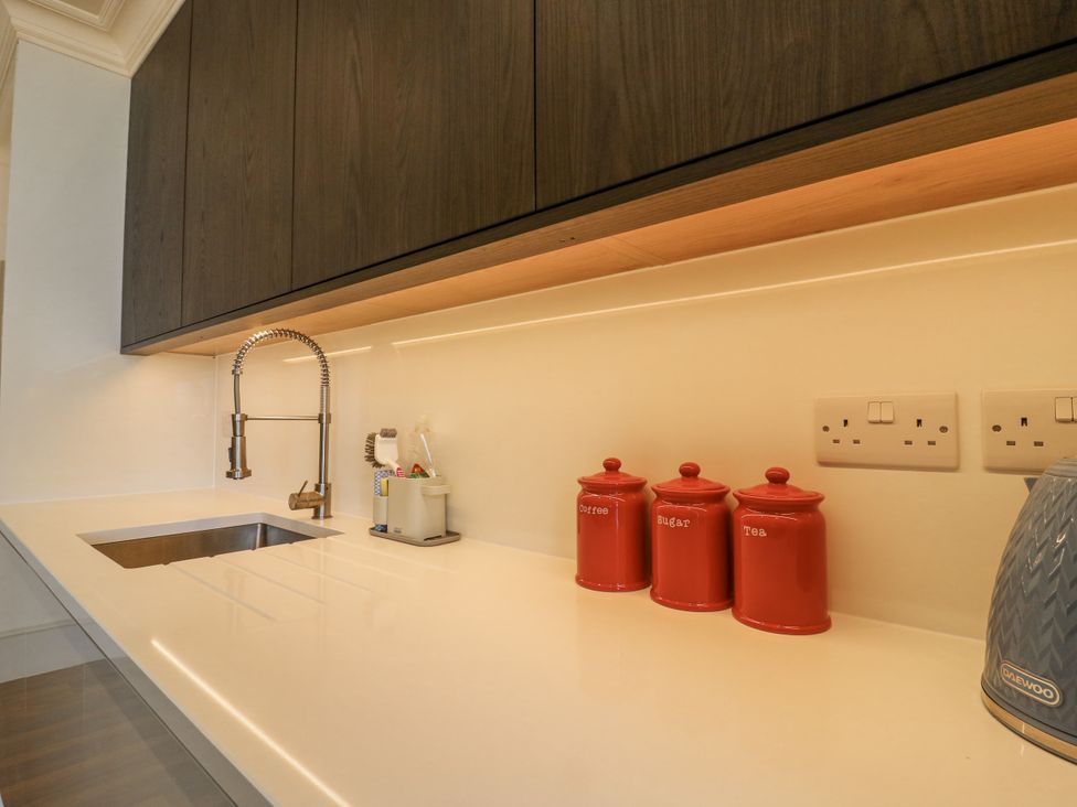 A kitchen with a sink and storage jars at Coast Guard House in Swalecliffe