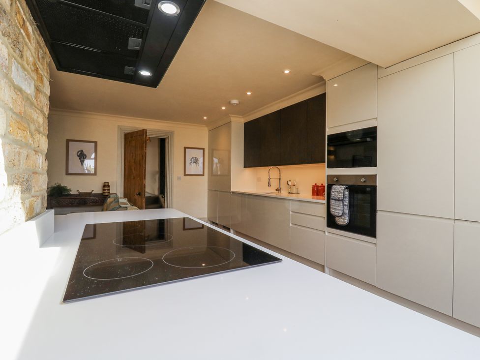 A kitchen with countertops, stove, and cabinets at Coast Guard House Swalecliffe