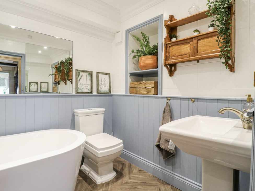 A bathroom with a bathtub, toilet, sink, and wall decor at Coast Guard House in Swalecliffe