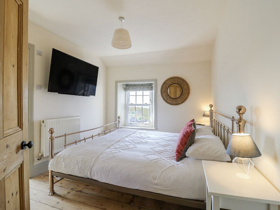 A bedroom with a bed and television at Coast Guard House in Swalecliffe