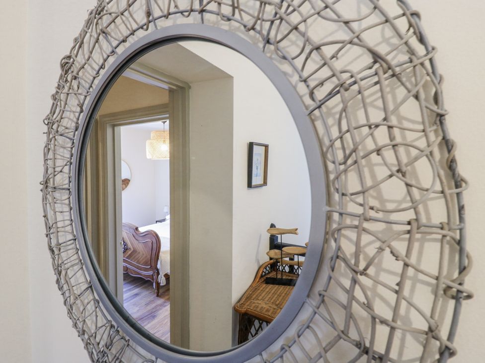 A mirror reflecting a bedroom with a bed and light fixture at Coast Guard House Swalecliffe