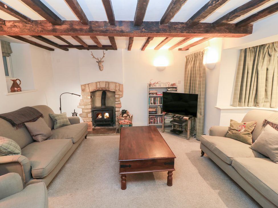 A living room with a fireplace and television at Butlers Cottage in Burford