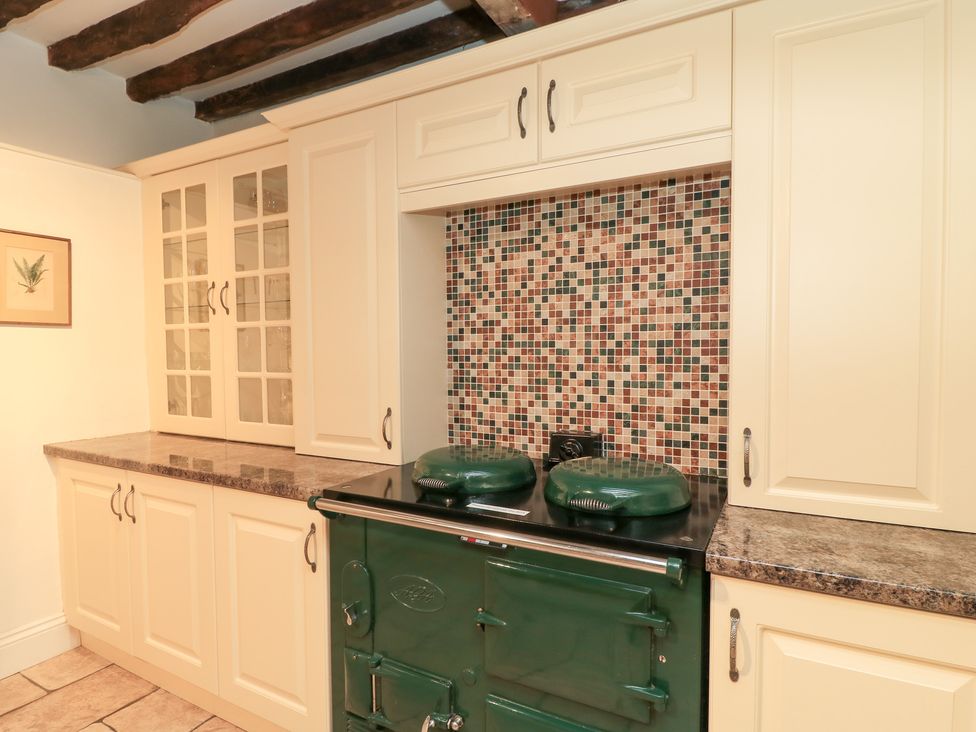 A kitchen with a green stove and mosaic backsplash at Butlers Cottage in Burford