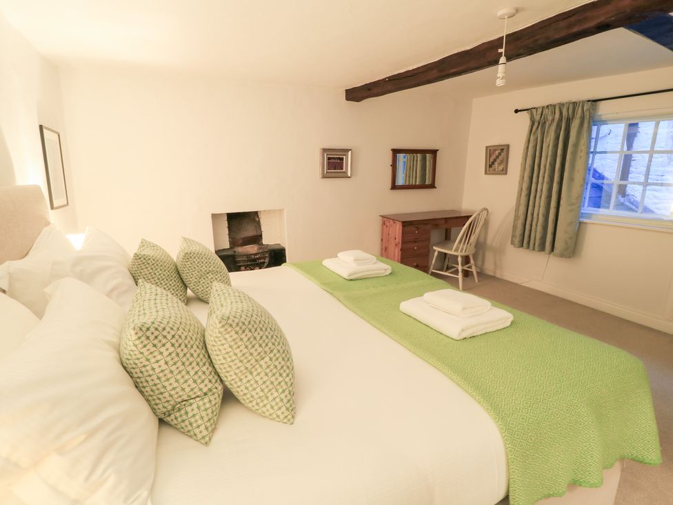 A bedroom with a bed and desk at Butlers Cottage in Burford