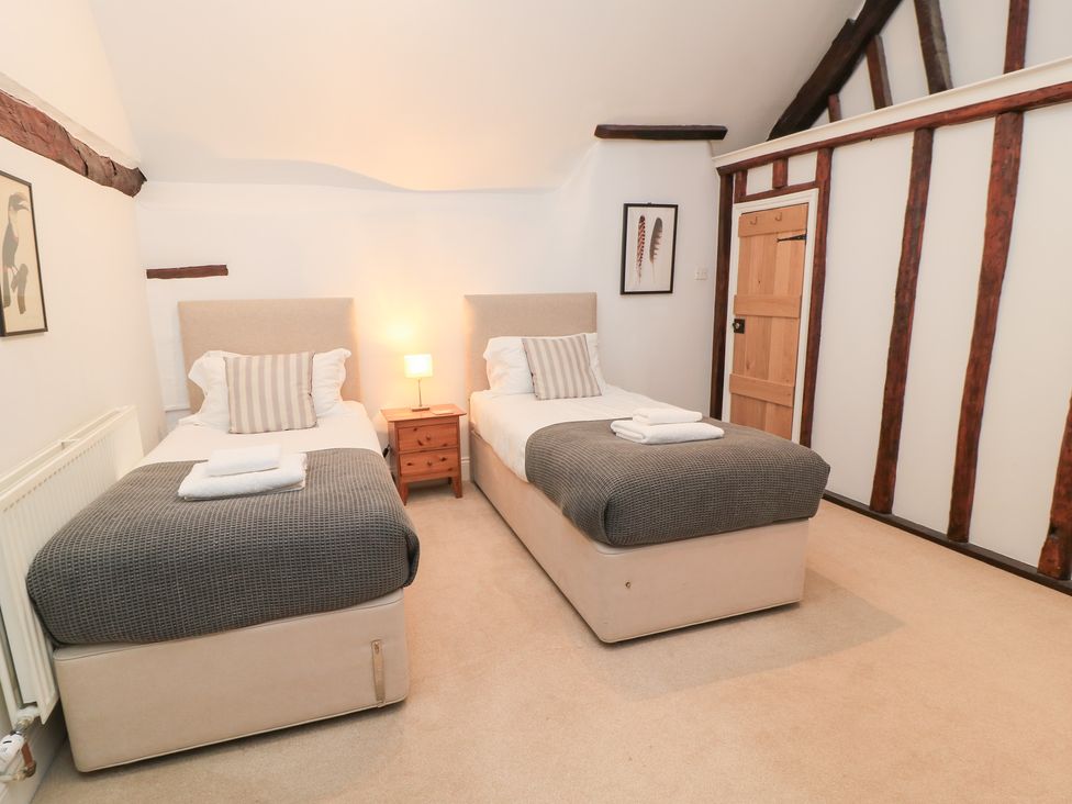 A bedroom with two single beds and a nightstand at Butlers Cottage in Burford