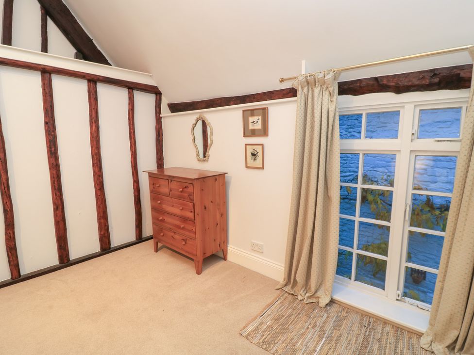 A bedroom with a chest of drawers and a window at Butlers Cottage, Burford