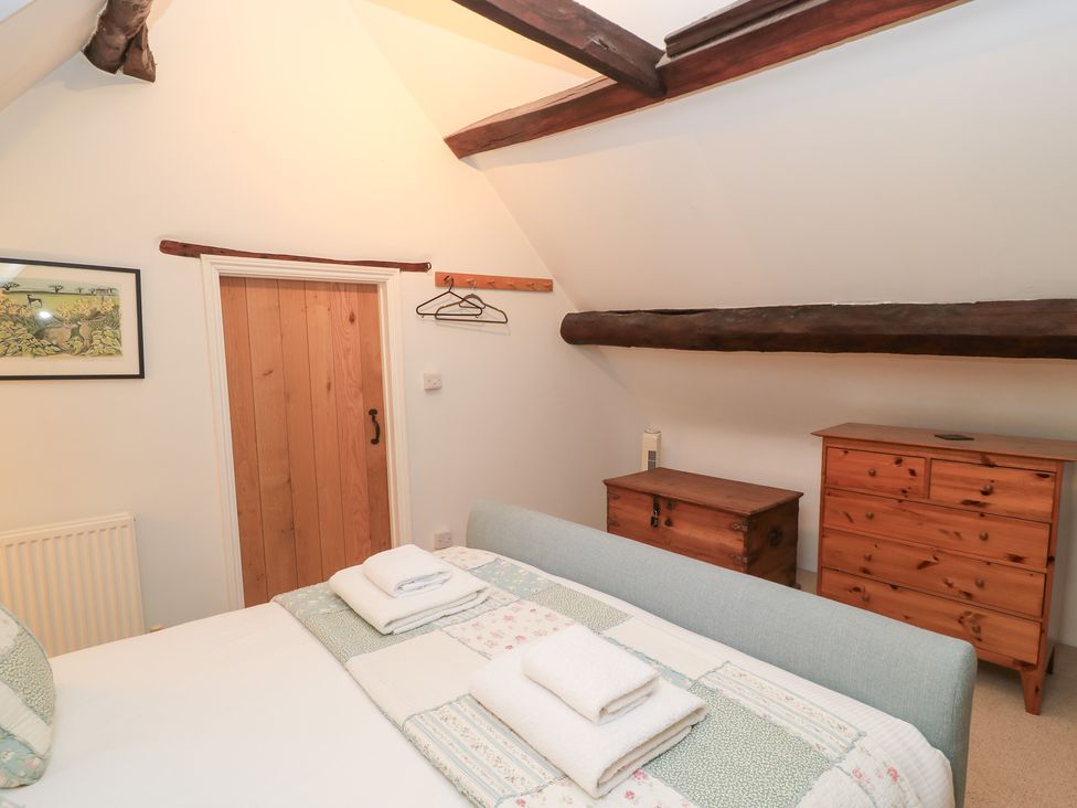 A bedroom with a bed and wooden furniture at Butlers Cottage in Burford