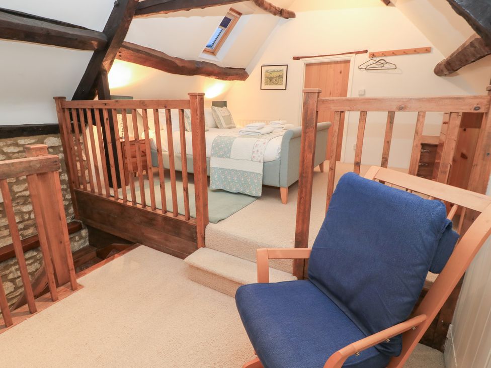 A bedroom with a bed and armchair at Butlers Cottage Burford
