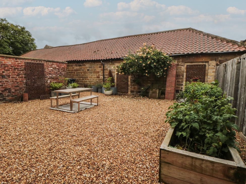 A garden with gravel, a table, and planters at Black Horse Cottage in Swainby