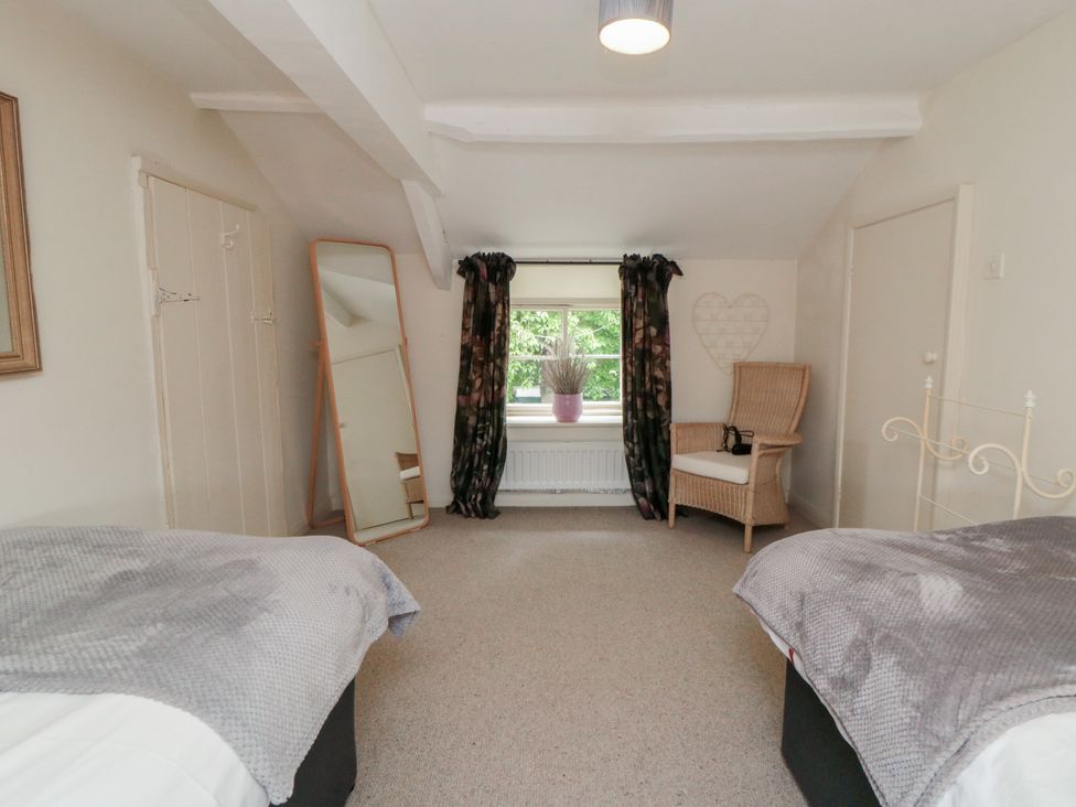 A bedroom with two beds and a mirror at Black Horse Cottage in Swainby