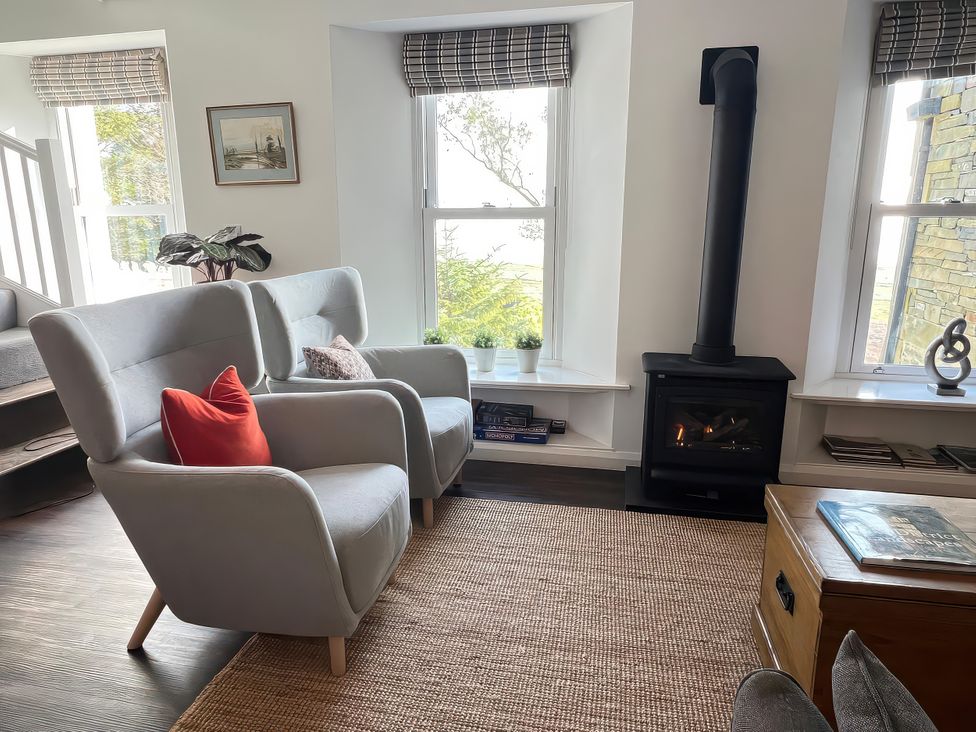 A living room with armchairs and a fireplace at Moorhurst Cottage Kents Bank near Grange-Over-Sands