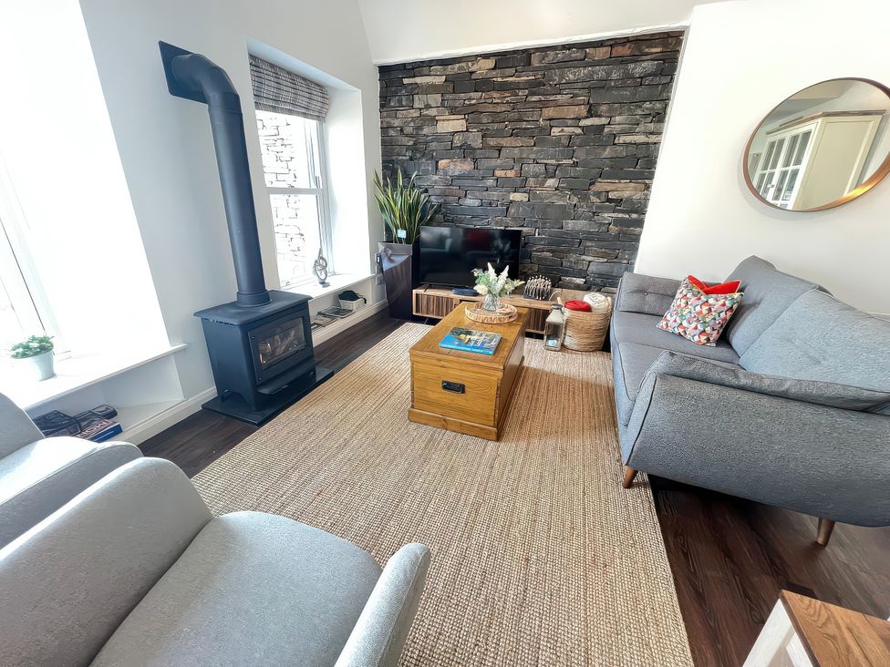 A living room with a wood stove and sofa at Moorhurst Cottage in Kents Bank near Grange-Over-Sands