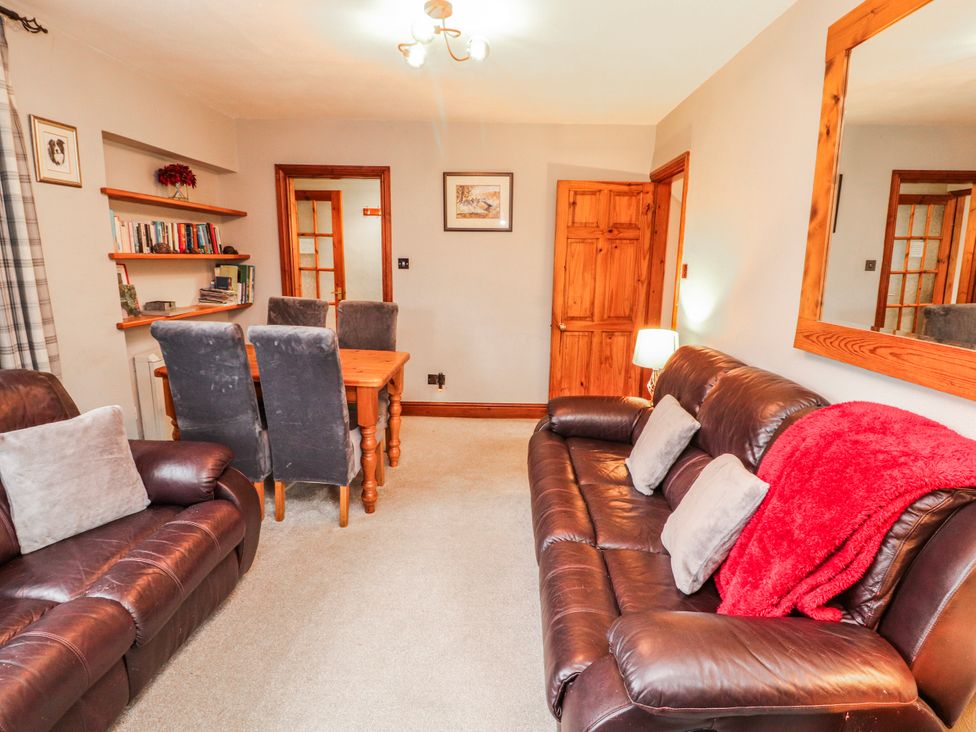 A living room with a sofa and dining area at Greenbank Cottage in Winster near Bowness-On-Windermere