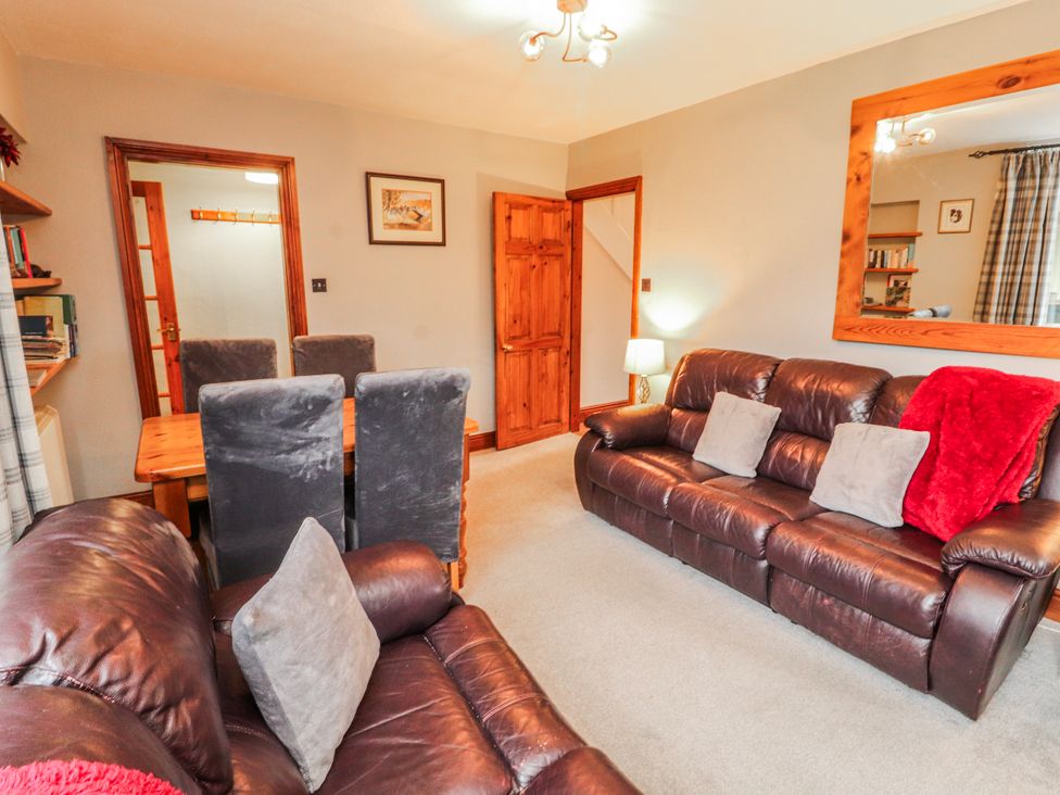 A living room with a sofa and dining table at Greenbank Cottage in Winster near Bowness-On-Windermere
