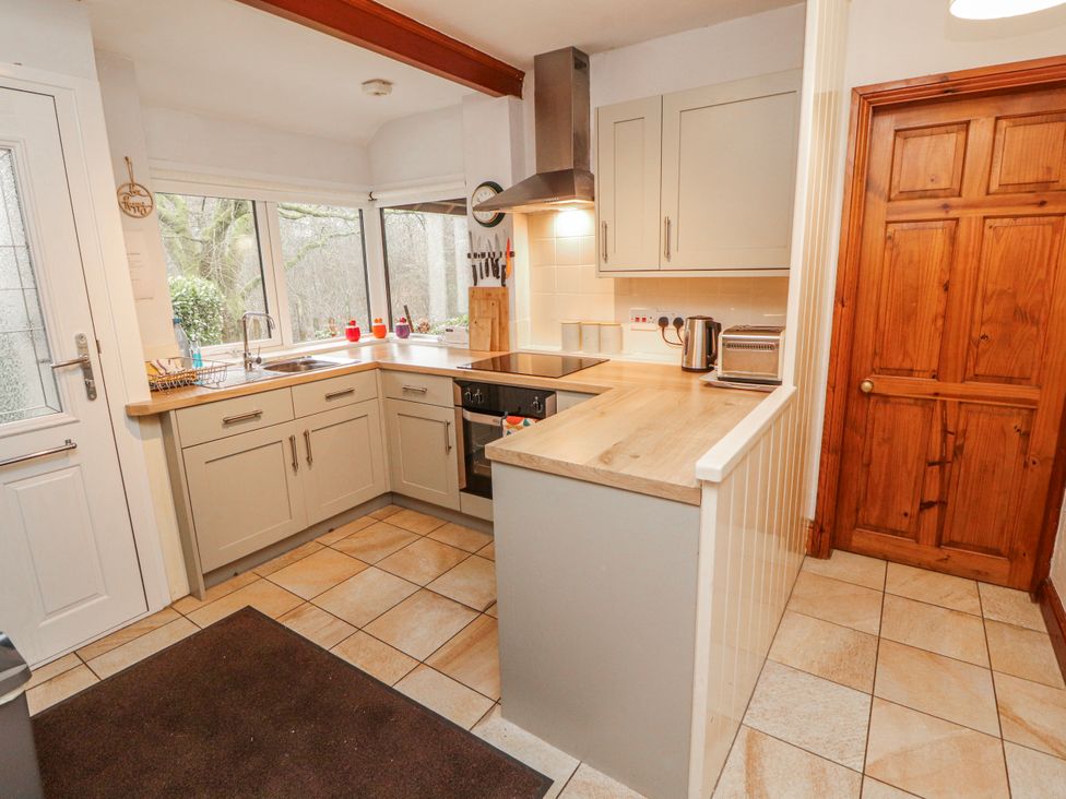 A kitchen with cabinets and appliances at Greenbank Cottage in Winster near Bowness-On-Windermere